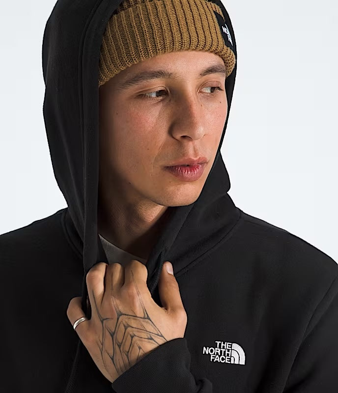 Person wearing a black hoodie with The North Face logo, holding hood up, on a white background