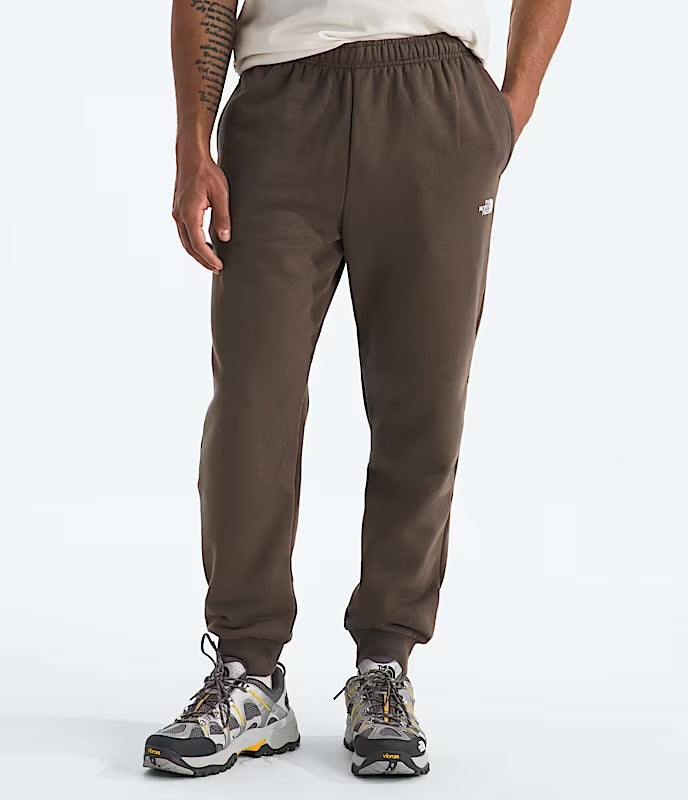 Brown jogger pants worn by a person on a white background