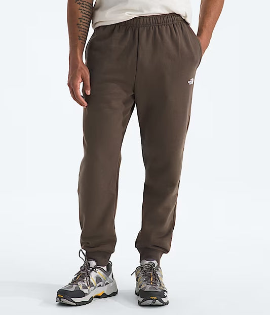 Brown jogger pants worn by a person on a white background