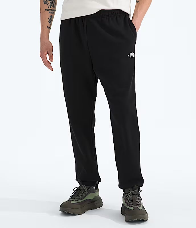 Person wearing black pants with a brand logo on a white background