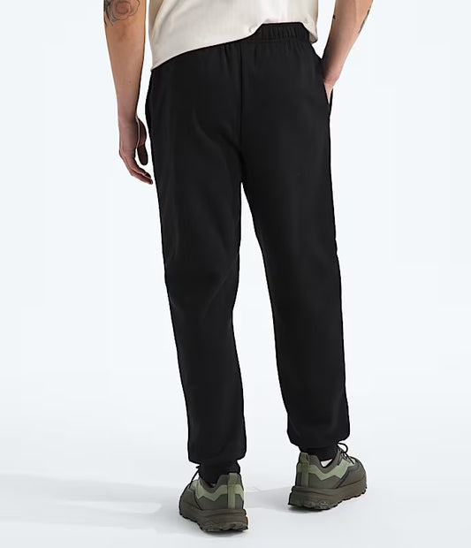 Person wearing black pants and green shoes on a white background