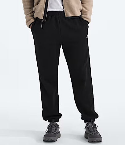 Person wearing a layered outfit with a jacket, shirt, pants, and sneakers on a white background. 