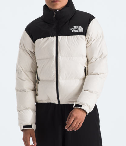 Person wearing a white and black North Face jacket on a light gray background 