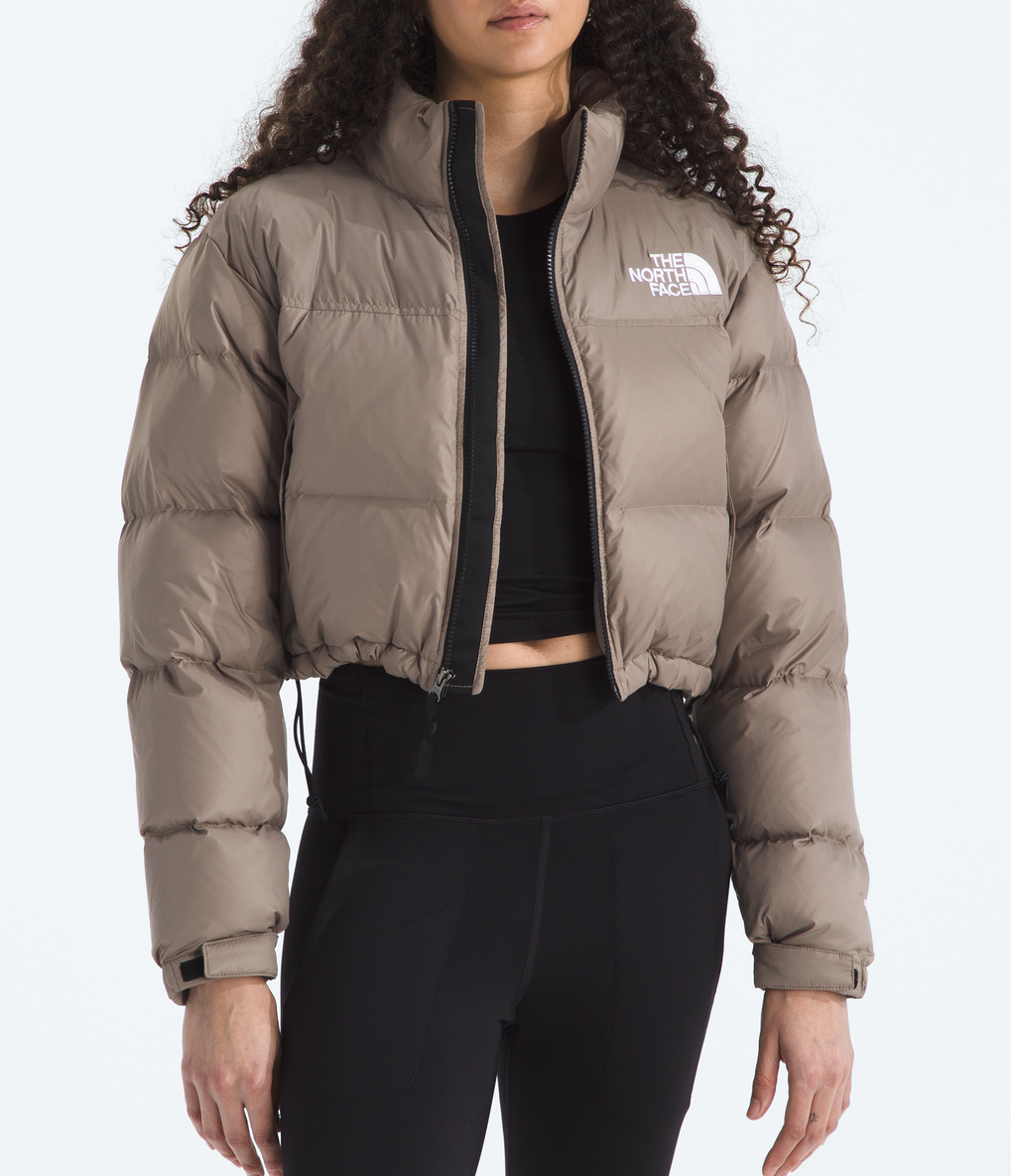 Woman wearing a beige puffer jacket with a brand logo on a white background 