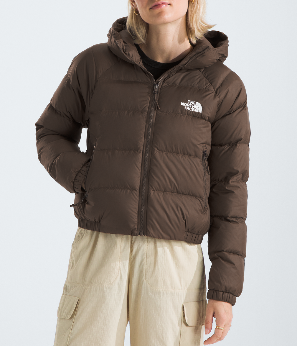 Person wearing a brown puffer jacket with a logo on a light gray background