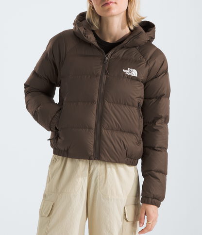 Person wearing a brown puffer jacket with a logo on a light gray background