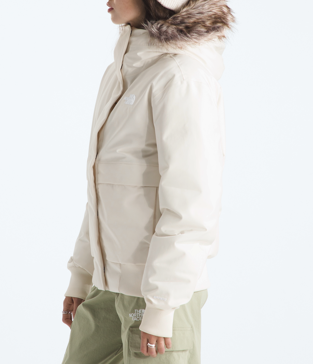 Person wearing a beige winter jacket with fur hood on a white background 