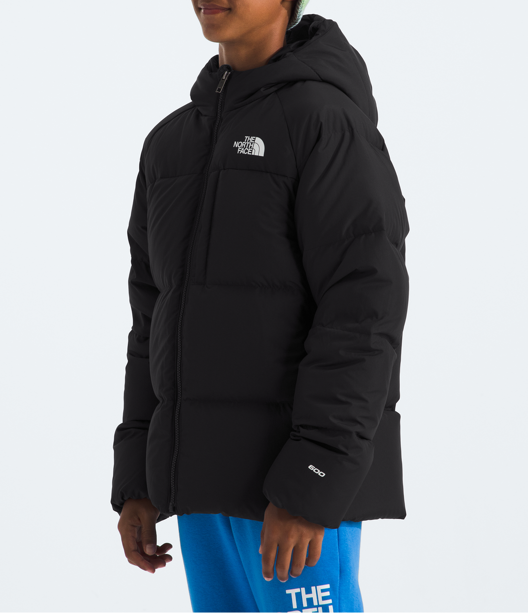 Person wearing a black The North Face jacket and blue pants with a patterned beanie on a white background