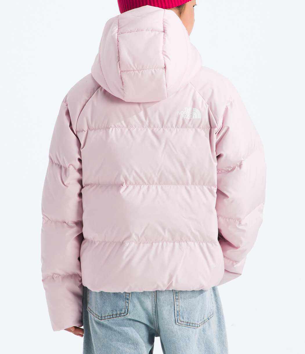 Person wearing a pink puffer jacket and red beanie on a white background