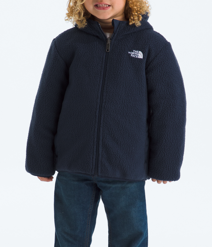 Child wearing a navy blue jacket and pants with a black beanie on a white background