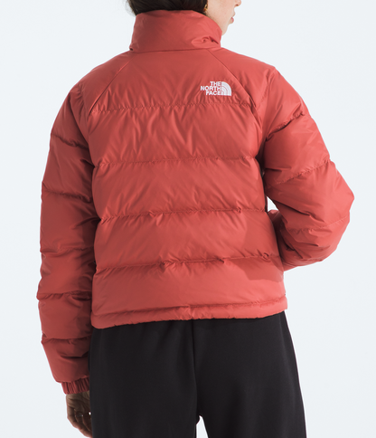 Person wearing a red puffer jacket with The North Face logo on a white background