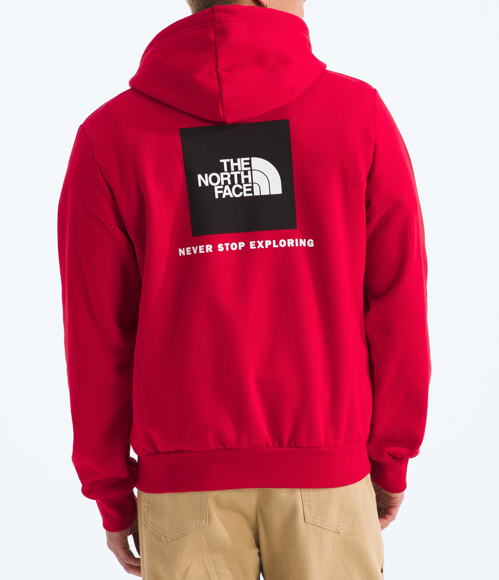 Person wearing a red hoodie with The North Face logo on the back, standing against a white background