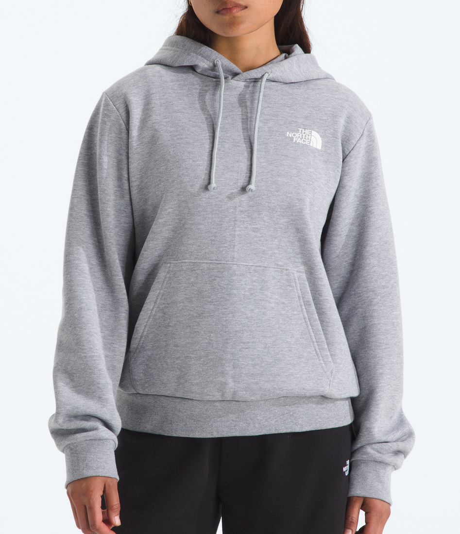 Person wearing a gray hoodie and black shorts with a floral cap on a white background