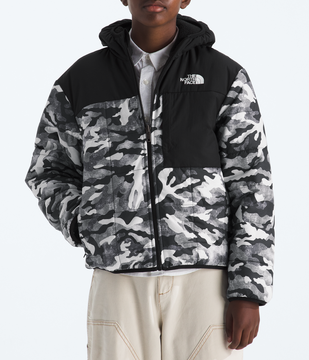 Person wearing a black and gray camouflage jacket with The North Face logo on a white background