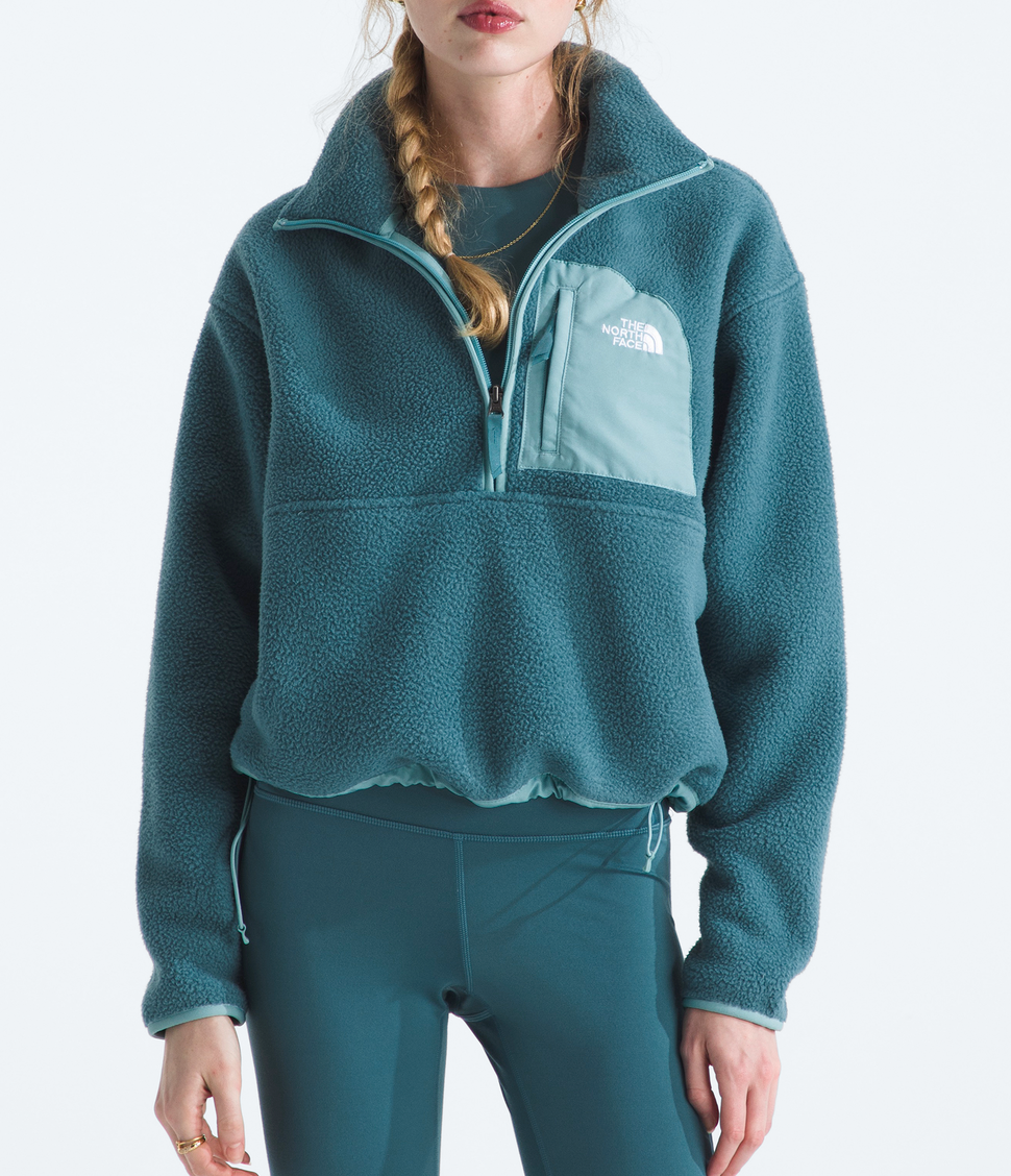 Person wearing a teal fleece pullover with a logo on a white background
