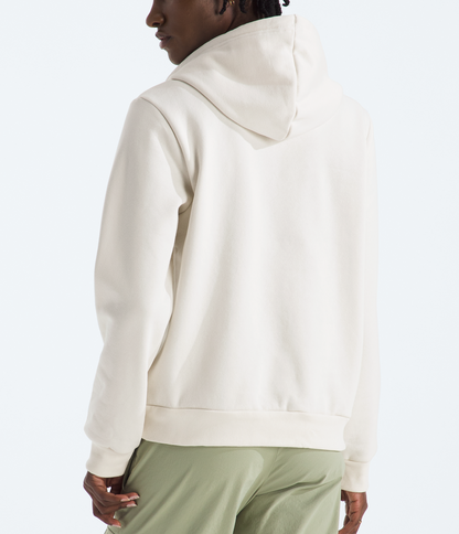 Person wearing a beige hoodie and green pants on a white background