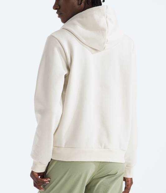Person wearing a beige hoodie and green pants on a white background