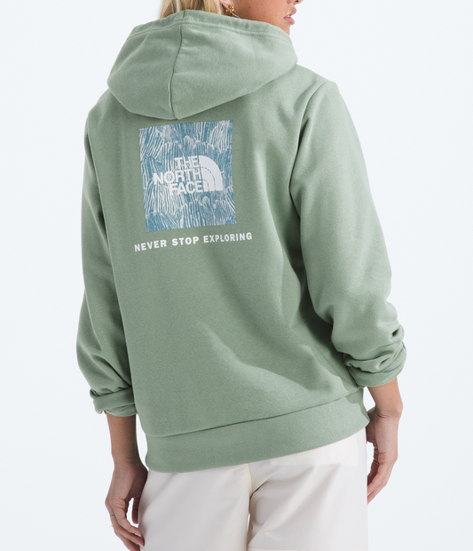 Person wearing a green hoodie with a brand logo on the back against a white background