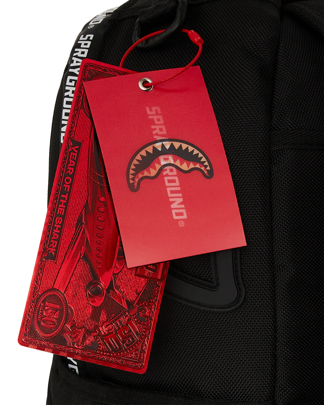Black backpack with a red 'Sprayground' tag featuring a shark logo.