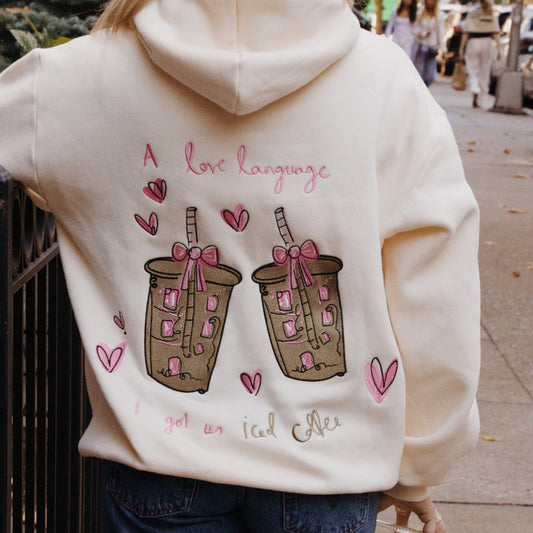 Person wearing a hoodie with a design of bubble tea cups and text on the back.