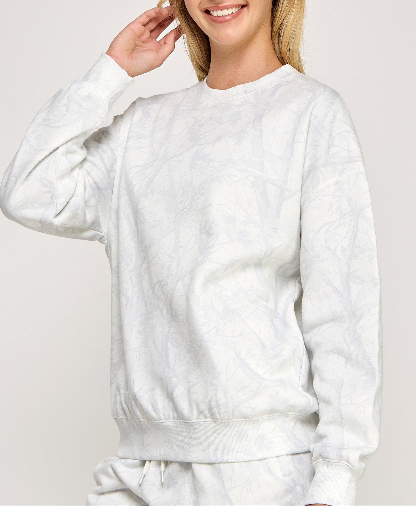 Person wearing a white sweatshirt on a plain background
